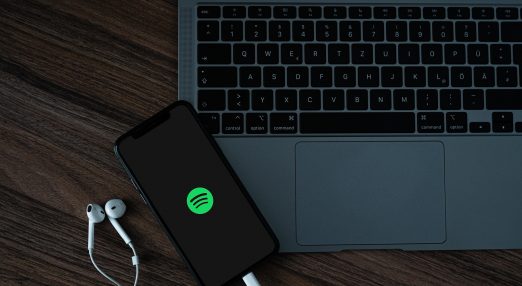 An image of a laptop and a phone displaying Spotify's logo