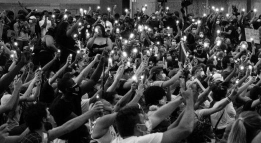 An black and white image showing a crowd of peopl with their phone flashes on