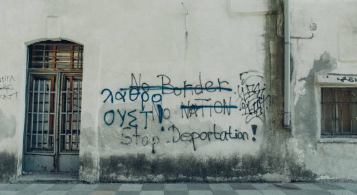 An image showing a wall with grafitti, where "No Border Nation" is crossed, and "Stop deportation!" is visbile.