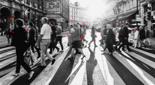 An image showing a group of people on a crossing with red squares that target their faces, mimicking facial recognition tools.