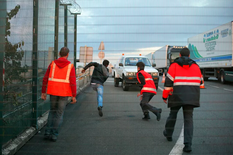 A person runs after crossing a fence in an attempt to access the Channel Tunnel, in Calais, July 2015