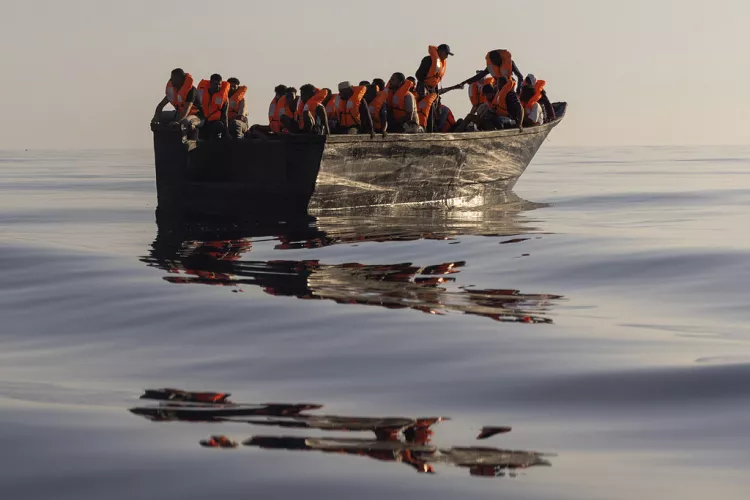 Migrants with life jackets sail in a wooden boat as they are being rescued some 26 nautical milessouth of the Italian Lampedusa island, August 2022